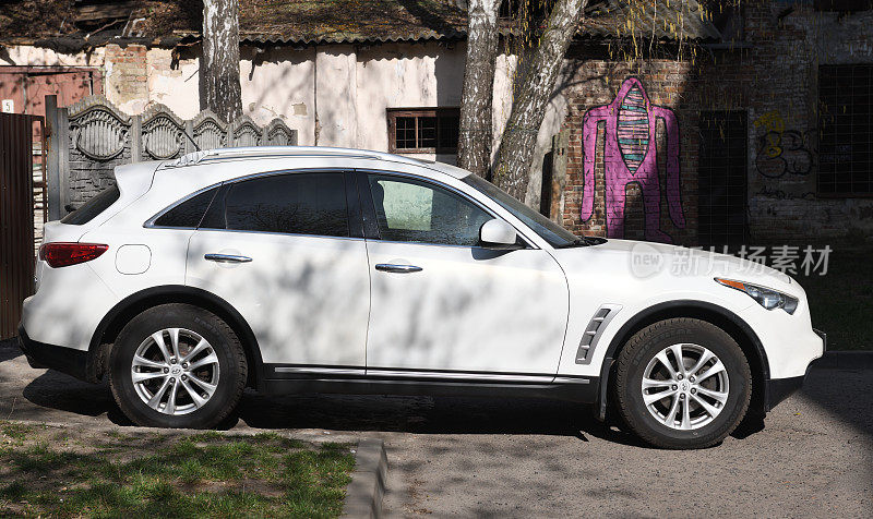 白色英菲尼迪FX35 FX45 FX50 QX70在塞巴斯蒂安维特尔限量版调谐侧视图在街边的停车场。